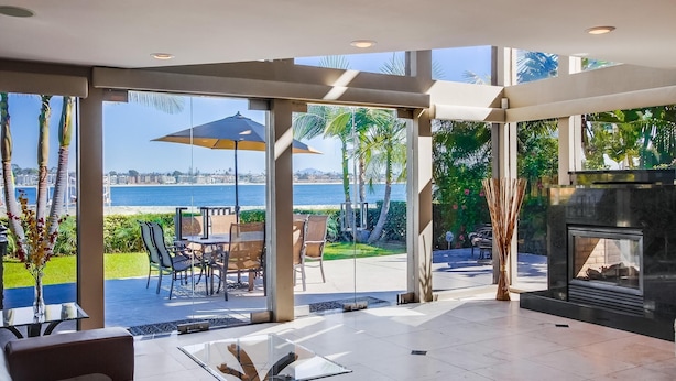 Amplia sala de estar con ventanas grandes, chimenea y zona de estar exterior junto a una piscina.