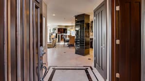 Un pasillo moderno con un pilar negro, una escalera y un comedor al fondo.