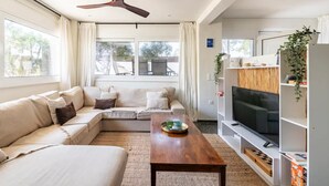 Una sala de estar moderna con un sofá, una mesa de centro, un televisor y un ventilador de techo.