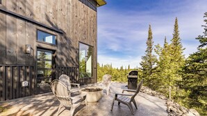 A wooden building with a patio area featuring outdoor seating and a fire pit. - Knife River Cabin with Amazing View and Sauna (Two Harbors)