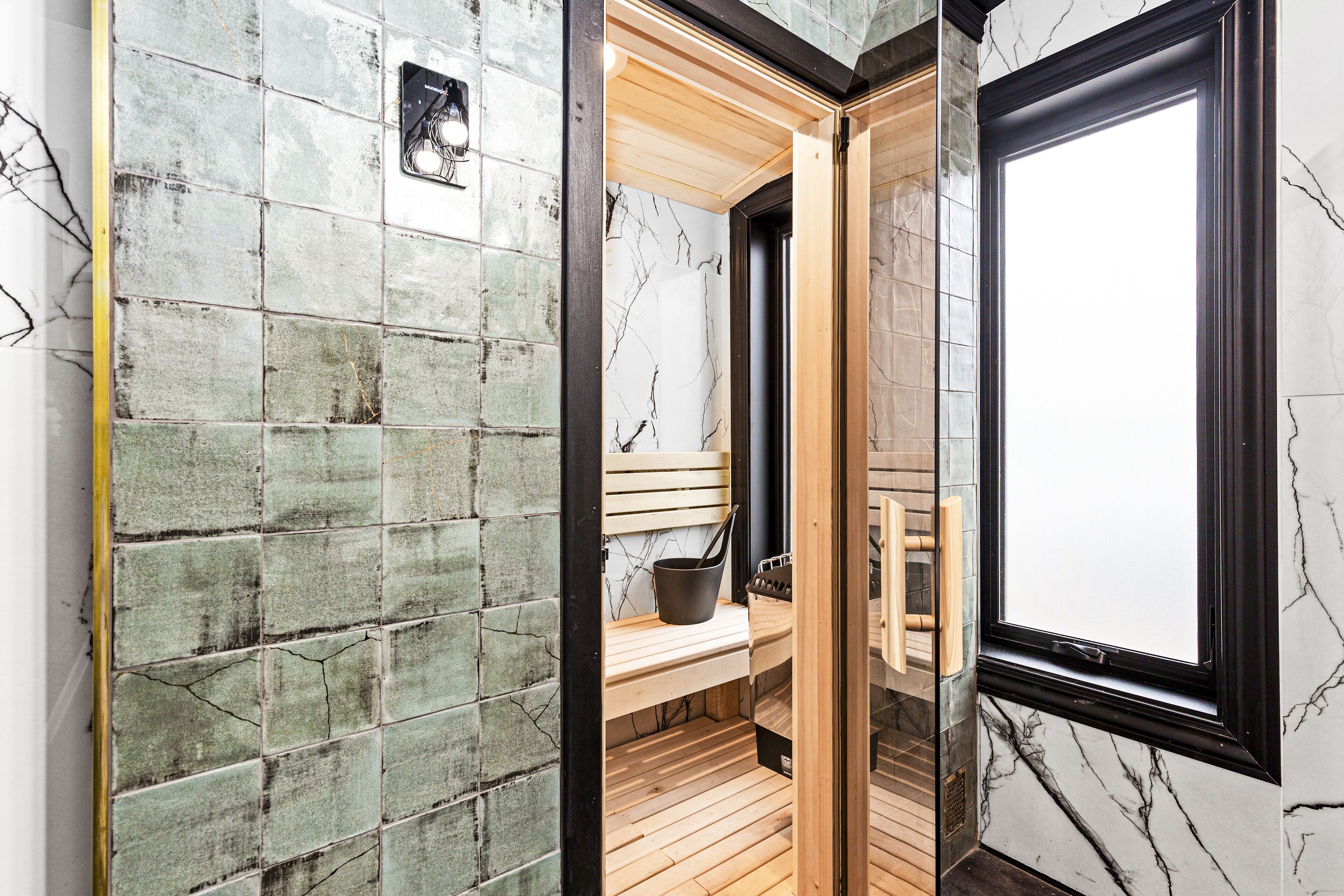A sauna with a wooden bench, a bucket, and a towel rack.