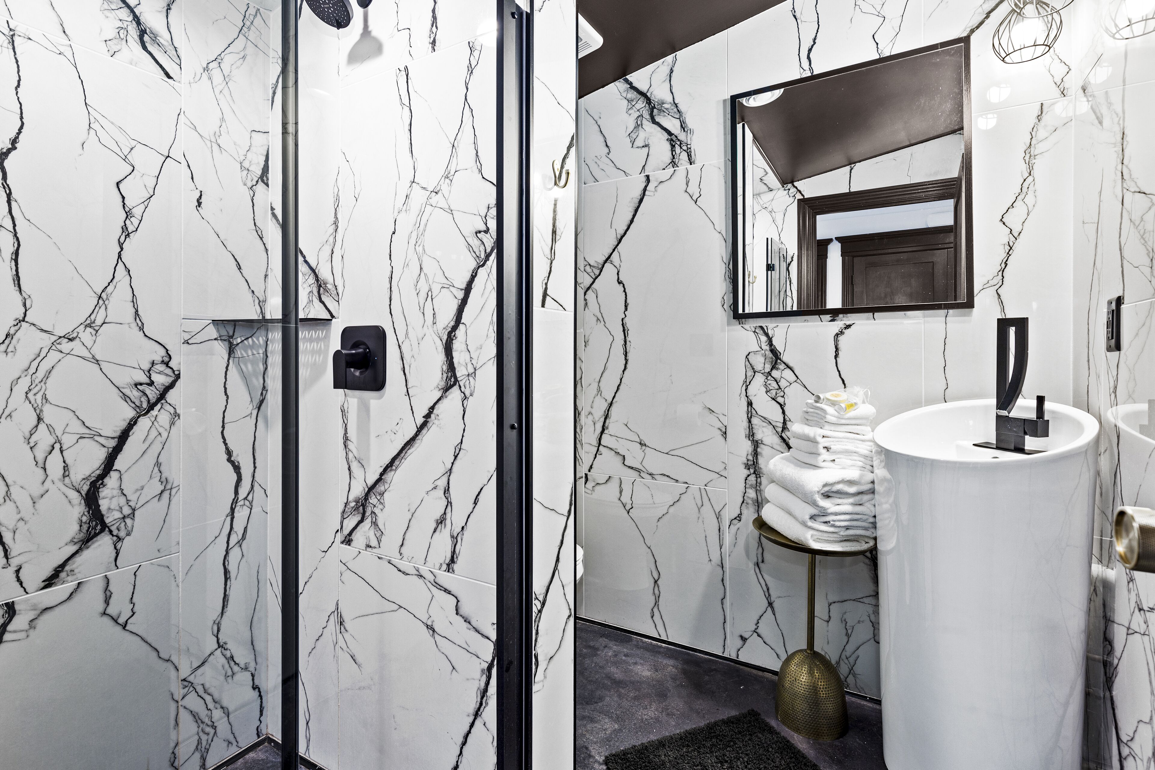 Une salle de bain avec des murs en marbre, un lavabo, un miroir et un porte-serviettes.