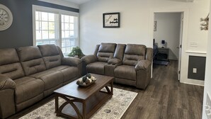 A living room with two brown leather sofas, a wooden coffee table, and a ceiling fan. - Cozy family retreat with great parking for multiple boats and vehicles! (Guntersville)