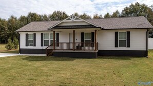 A single-story house with a front porch, a small deck, and a well-maintained lawn. - Cozy family retreat with great parking for multiple boats and vehicles! (Guntersville)