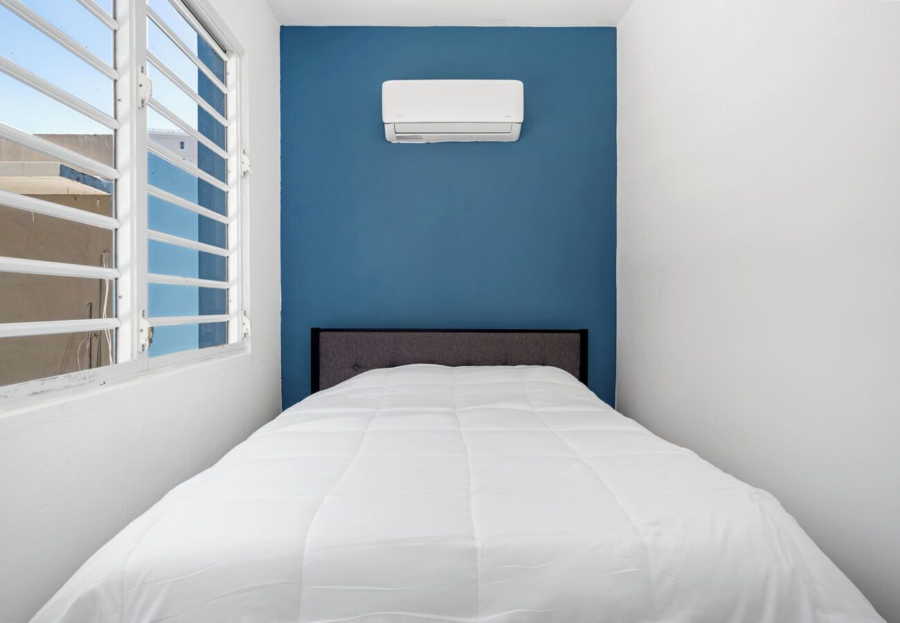 Quarto com uma cama, janela com persianas e ar condicionado na parede.