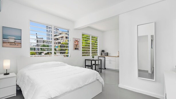 Un dormitorio moderno con una cama grande, un escritorio y vistas al exterior a través de amplios ventanales.