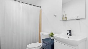 Un baño moderno con inodoro, lavabo y cortina de ducha.