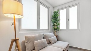 Un dormitorio moderno con sofá cama, una lámpara de pie y una planta en maceta.