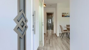 A modern interior with a glass shower, a dining area, and a geometric door design.