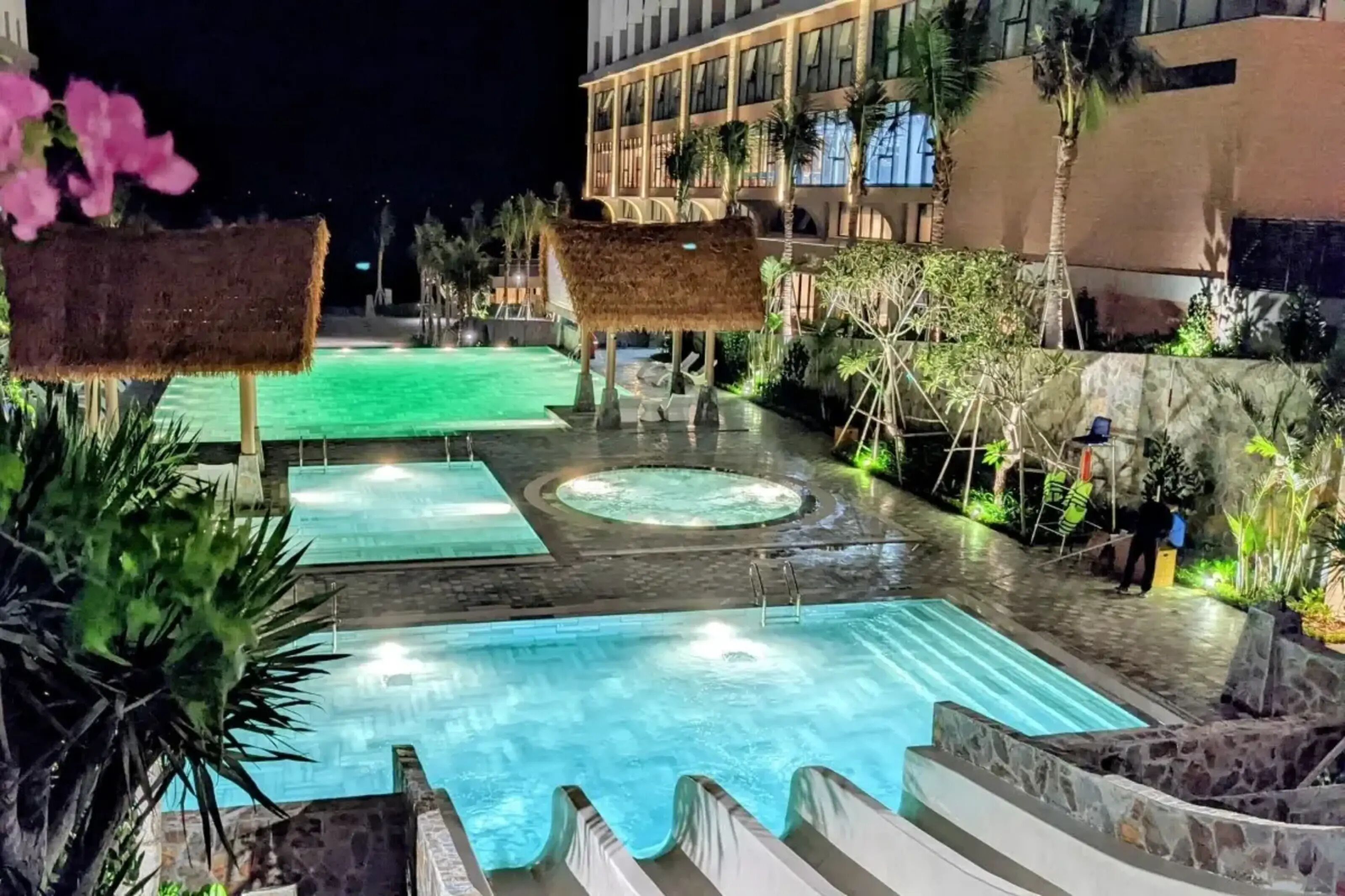 A pool area with a hot tub, lounge chairs, and a palm tree.
