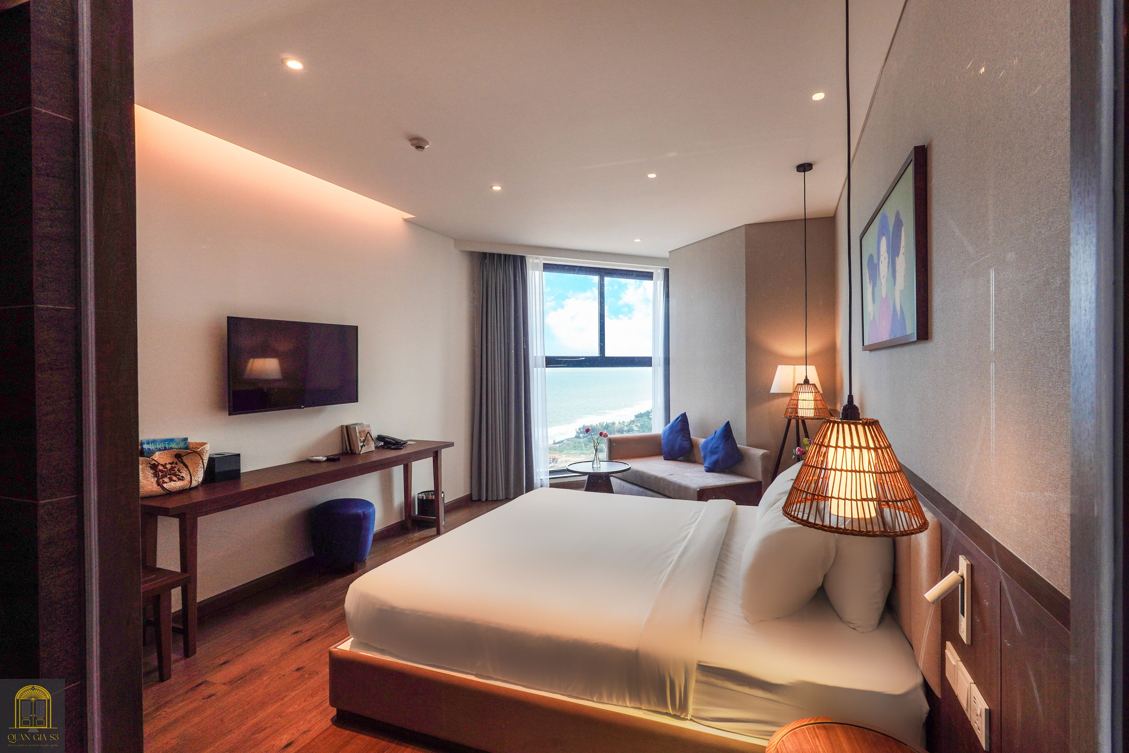 Ein modernes Hotelzimmer mit einem großen Bett, einem Schreibtisch, einem Fernseher und Blick ins Freie.