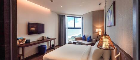 Ein modernes Hotelzimmer mit einem großen Bett, einem Schreibtisch, einem Fernseher und Blick ins Freie.