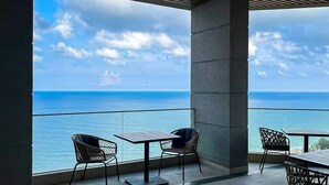 A balcony with a view of the ocean, featuring two tables and two chairs. - Apec Mandala Beach Mui Ne Resort (Mui Ne)