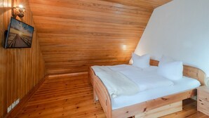 Une pièce aux murs lambrés, comprenant un lit, une table de chevet et une lampe fixée au mur.