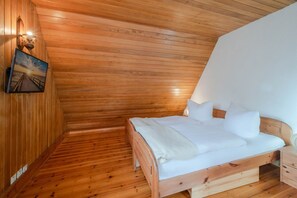 Ein Zimmer mit Holzwänden, einem Bett, einem Nachttisch und einer Wandlampe.