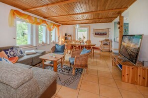Ein gemütliches Wohnzimmer mit Holzboden, einem Essbereich mit Stühlen und Tisch sowie einem Fernseher auf einem Holzboden.