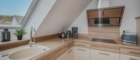 A modern kitchen with a built-in stove, a sink, and a window above the counter.