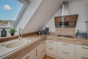 Eine moderne Küche mit Einbauherd, Spüle und einem Fenster über der Arbeitsfläche.
