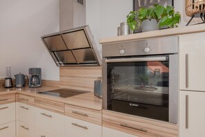 A modern kitchen with a Bosch oven, a coffee maker, and a built-in range hood.