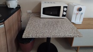 Una kitchenette compacta con microondas, tostadora y dispensador de agua en la encimera.