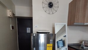 Una cocina compacta con un refrigerador de acero inoxidable, un microondas y armarios de madera.