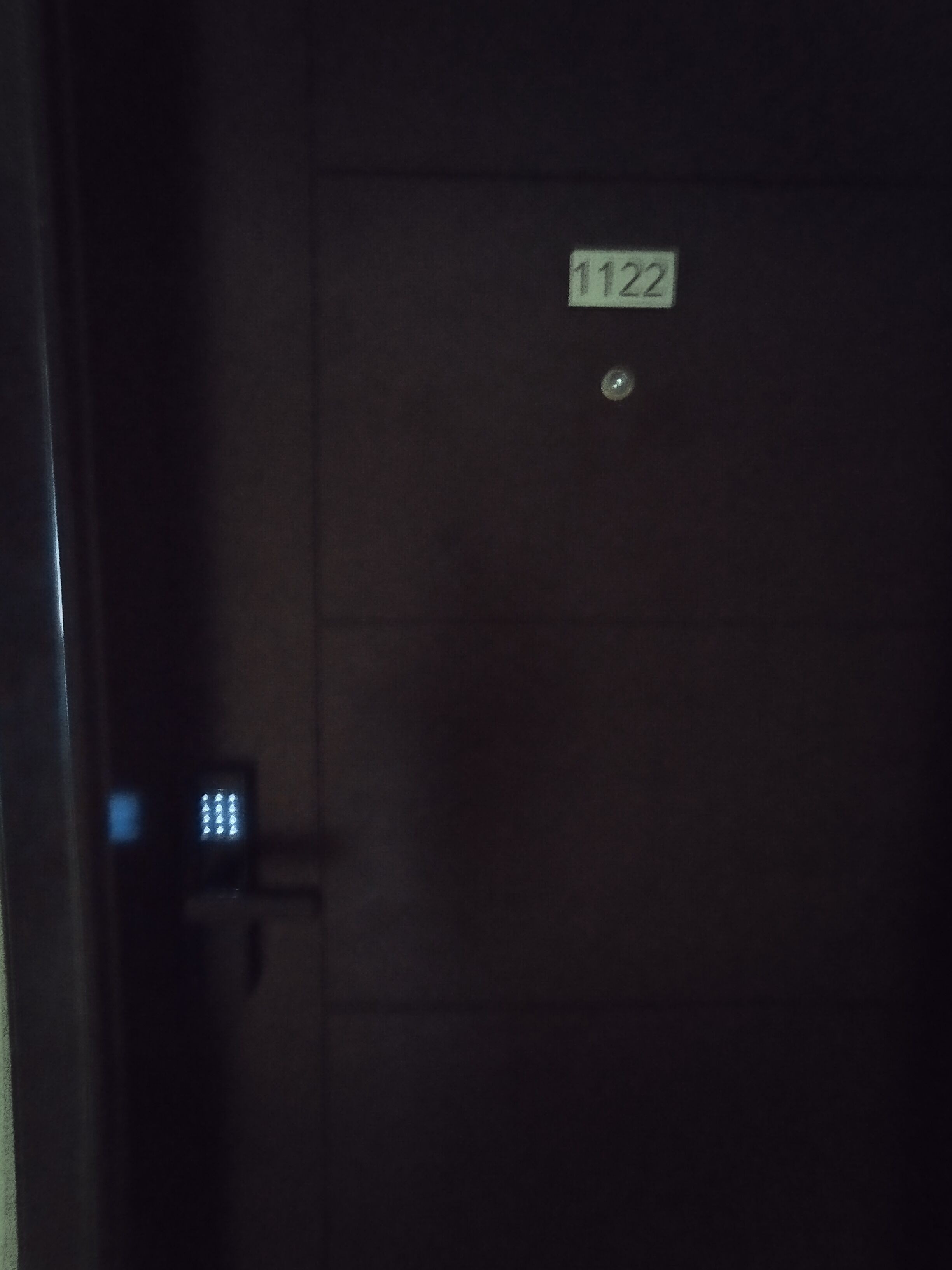 Ein dunkler Raum mit einer Tür, auf der „1122“ steht.