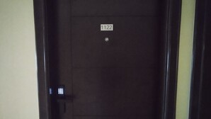 Una puerta de madera oscura con una etiqueta que dice "1122" y un objeto metálico pequeño y redondo en su superficie.