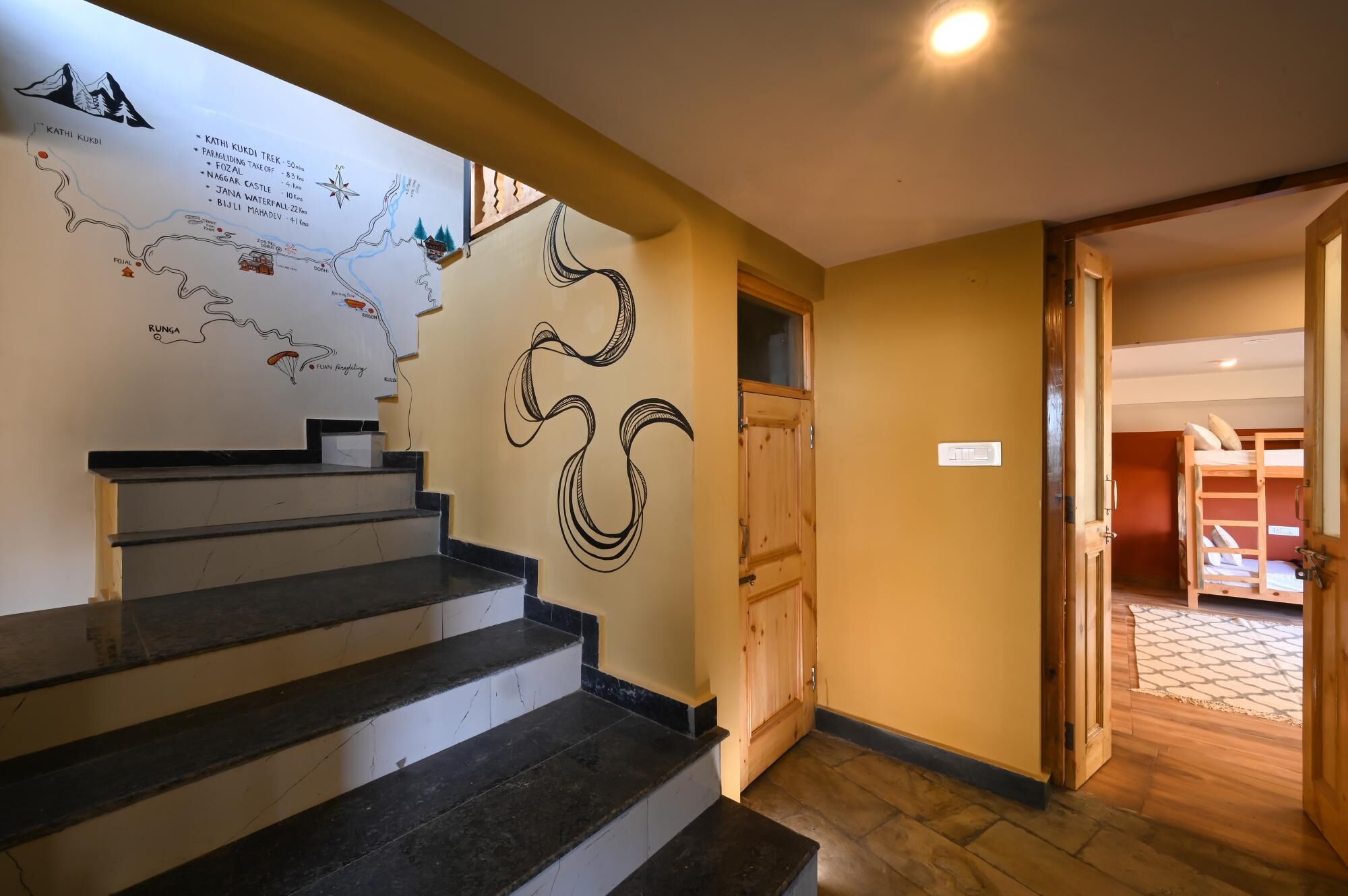 A staircase with a map and a stylized design on the wall, leading to a room with a bunk bed.