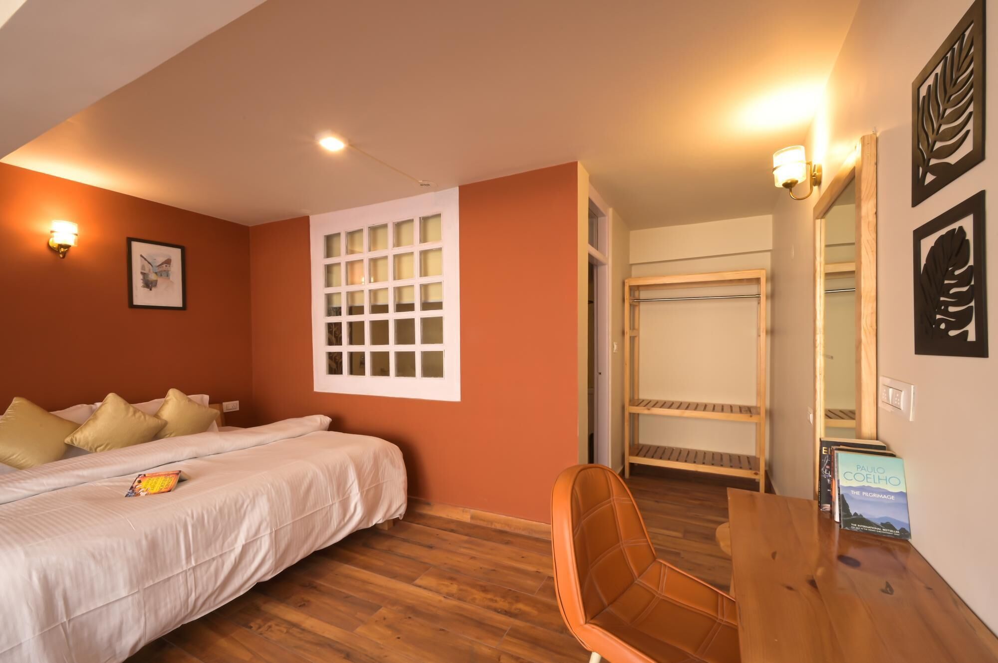 A bedroom with a bed, a chair, a desk, a wardrobe, and a window.