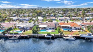 A coastal residential area with houses, a swimming pool, and boats docked at the marina. - 3402 Managed By Brampton Park (Pompano Beach)
