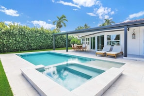 A rectangular swimming pool with a patio area, a covered seating area with chairs and a table, and a view of a modern house with large windows. - 3402 Managed By Brampton Park (Pompano Beach)
