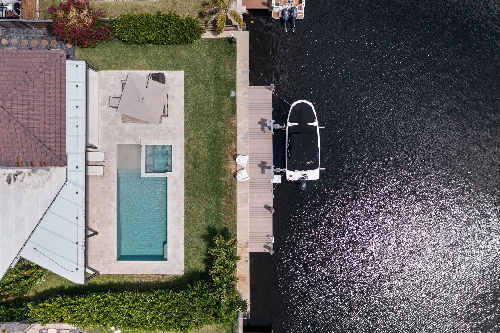 Vista aérea de una propiedad residencial con piscina, muelle y barco.