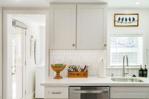 Een keuken met witte kastjes, een roestvrijstalen spoelbak en een afwasschaal.