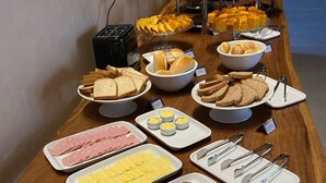 Un buffet proposant une variété d’aliments, notamment du pain, du fromage, de la charcuterie et des fruits.