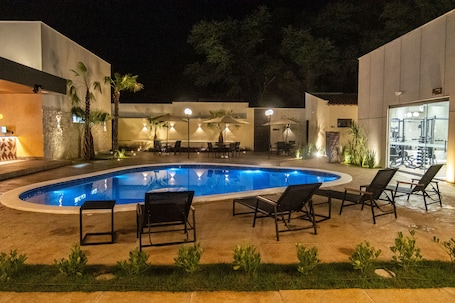 Una piscina al aire libre, sombrillas, sillones reclinables de piscina