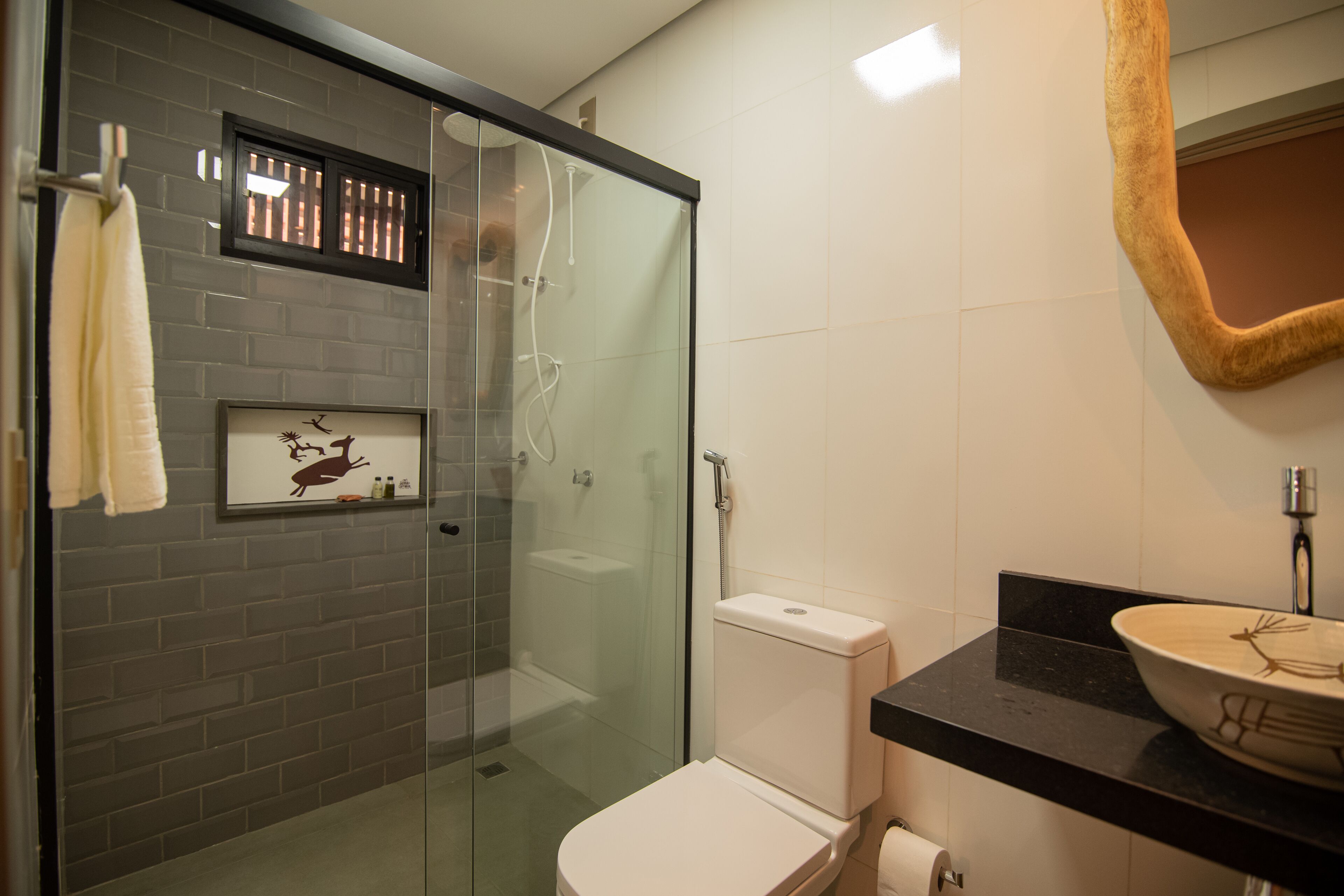 A bathroom with a glass-enclosed shower, a toilet, and a sink with a decorative bowl.