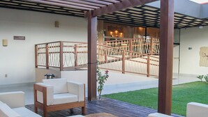 Un espace extérieur abrité, aménagé avec du mobilier en bois et une petite table ronde.