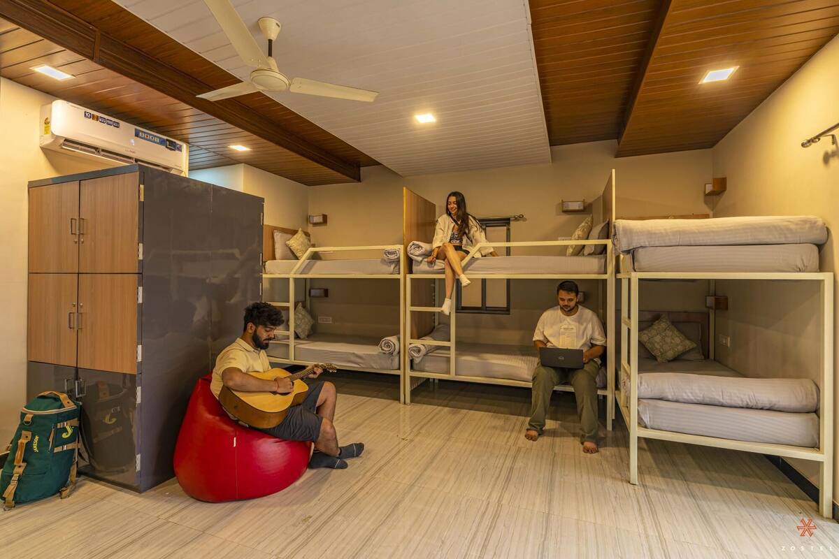 A dormitory room with bunk beds, a ceiling fan, and a wardrobe.