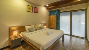 A bedroom with a wooden bed, nightstands, a large window with curtains, and two framed pictures on the wall. - Zostel Kolad (Roha)