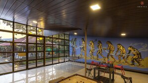 A spacious indoor area with a foosball table, a mural depicting human evolution, and large windows offering a view of the outdoors. - Zostel Kolad (Roha)