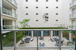 A modern building with a courtyard featuring outdoor seating and a sculpture.