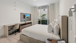 A hotel room with a bed, a desk with a chair, a TV, a balcony with curtains, and a phone. - CH Luxury Studio With a Quiet Courtyard View-CS34 (Hollywood)