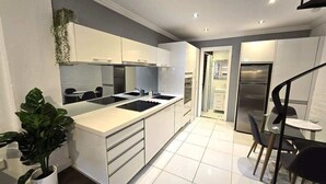 A modern kitchen with white cabinetry, a central island, and a dining area with a small table and chairs.