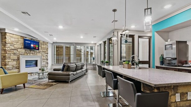 A modern kitchen with a stone accent wall, a built-in island, and a large window. - Modish Keen King Bed w/ Pool (Houston)