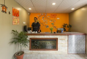 A reception desk with a map of the Annapurna Circuit Trek, a potted plant, and a fish tank. - Zostel Pokhara (Pokhara)