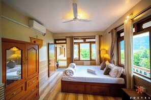A bedroom with a large bed, wooden furniture, and a view of greenery outside. - Zostel Pokhara (Pokhara)