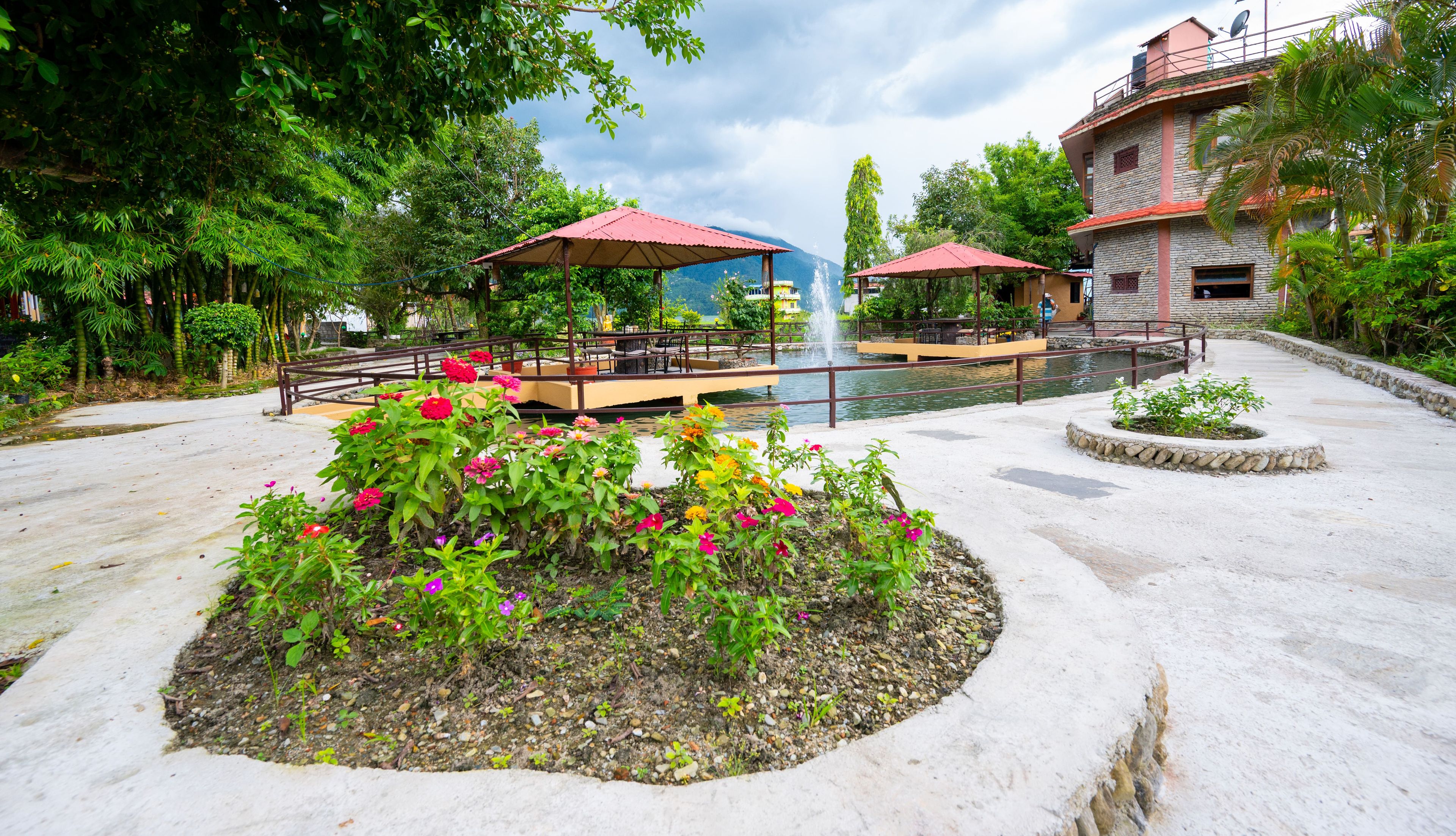 A courtyard with a fountain, outdoor seating, and a flower bed.
