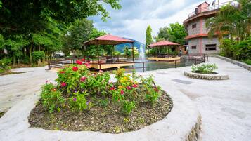 A courtyard with a fountain, outdoor seating, and a flower bed.