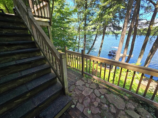 Un escalier en bois mène à une terrasse d’où l’on a vue sur un lac où se trouvent des bateaux.