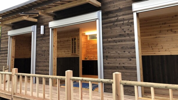 A wooden cabin with large windows and a deck.